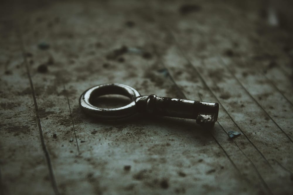 photo of an old key on a dirty floorboar